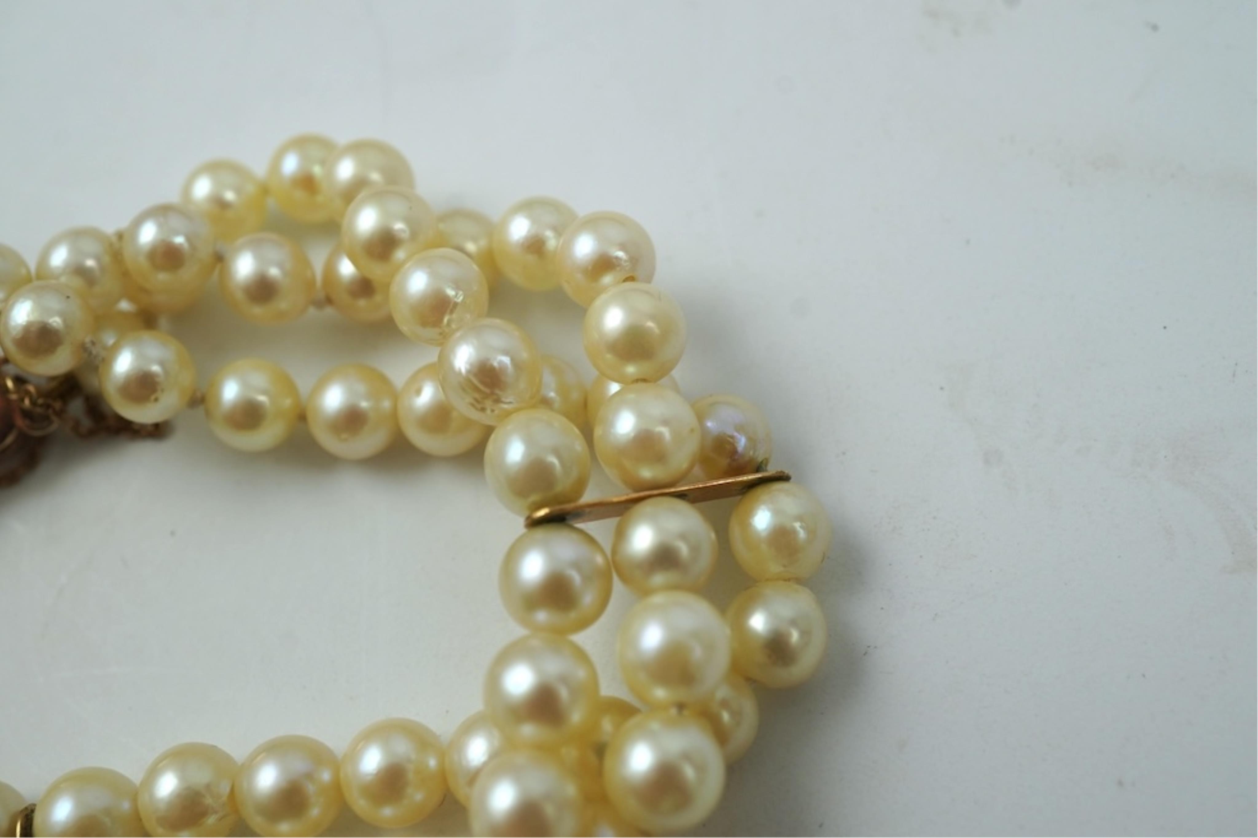 A triple strand cultured pearl bracelet, with a 9ct gold, garnet and cultured pearl cluster set clasp, 16cm.